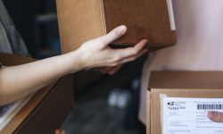 Close-up of hands exchanging cardboard delivery packages indoors.