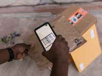 A person scans package barcodes using a smartphone for delivery logistics.